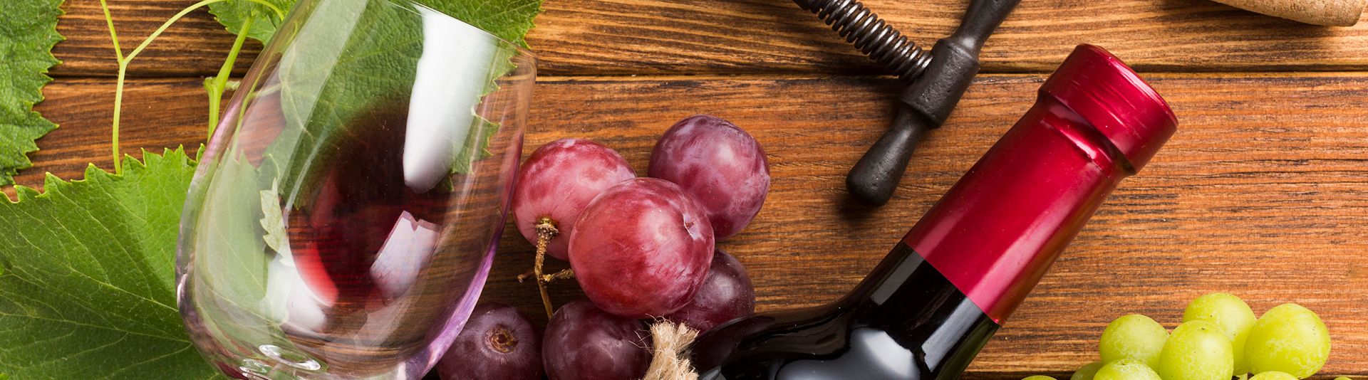 Vaso de vino, uvas y botella en la mesa.