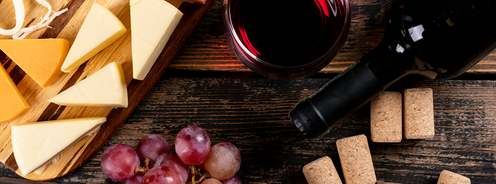 Cheese tray, grapes and wine on a wooden table.