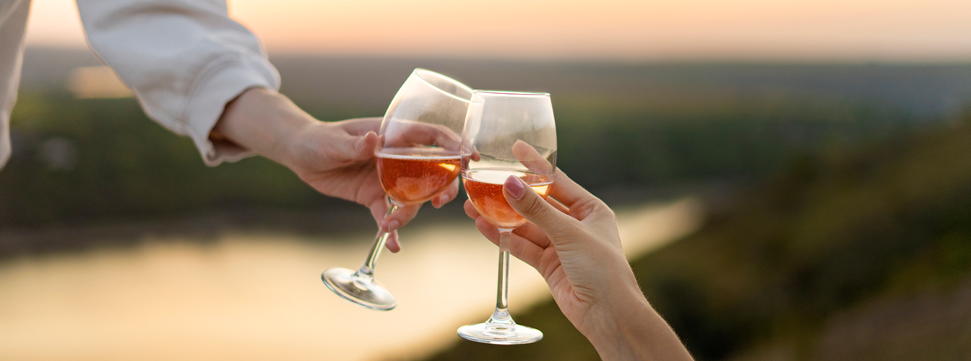 Two glasses of rosé wine toast at sunset.