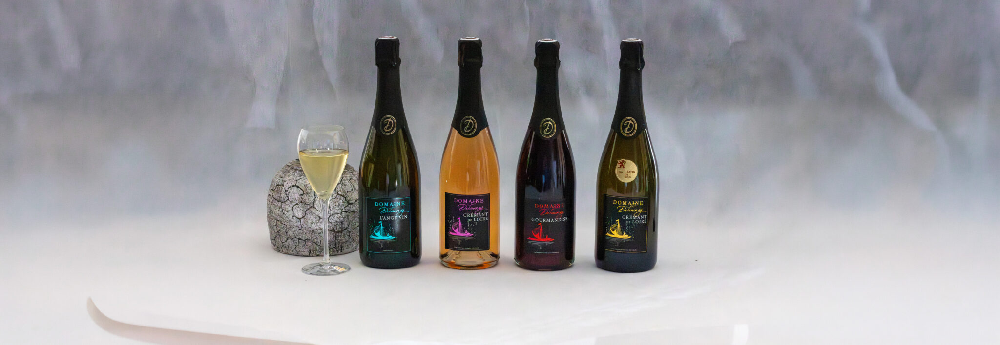 Quatre bouteilles de vin avec verre de vin blanc.